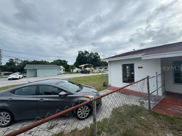 A gray sedan is parked on a concrete driveway next to a white house — 5018 GRAND BOULEVARD, NEW PORT RICHEY, FL