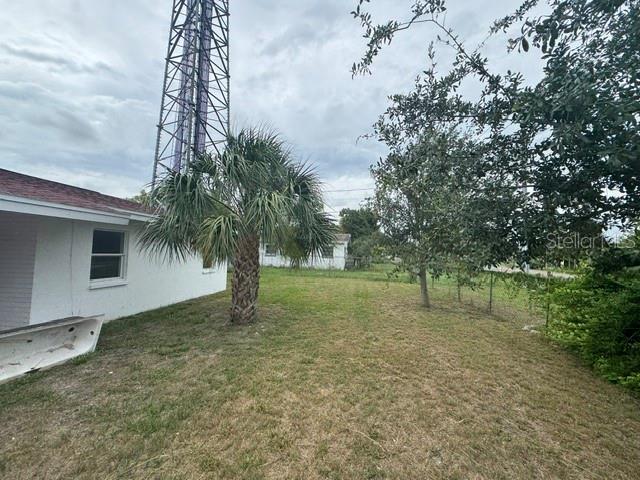 A backyard view features a white house, a palm tree, and a tall metal tower — 5018 GRAND BOULEVARD, NEW PORT RICHEY, FL