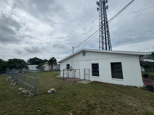 A white, single-story building with a fenced yard and a tall communications tower behind it — 5018 GRAND BOULEVARD, NEW PORT RICHEY, FL