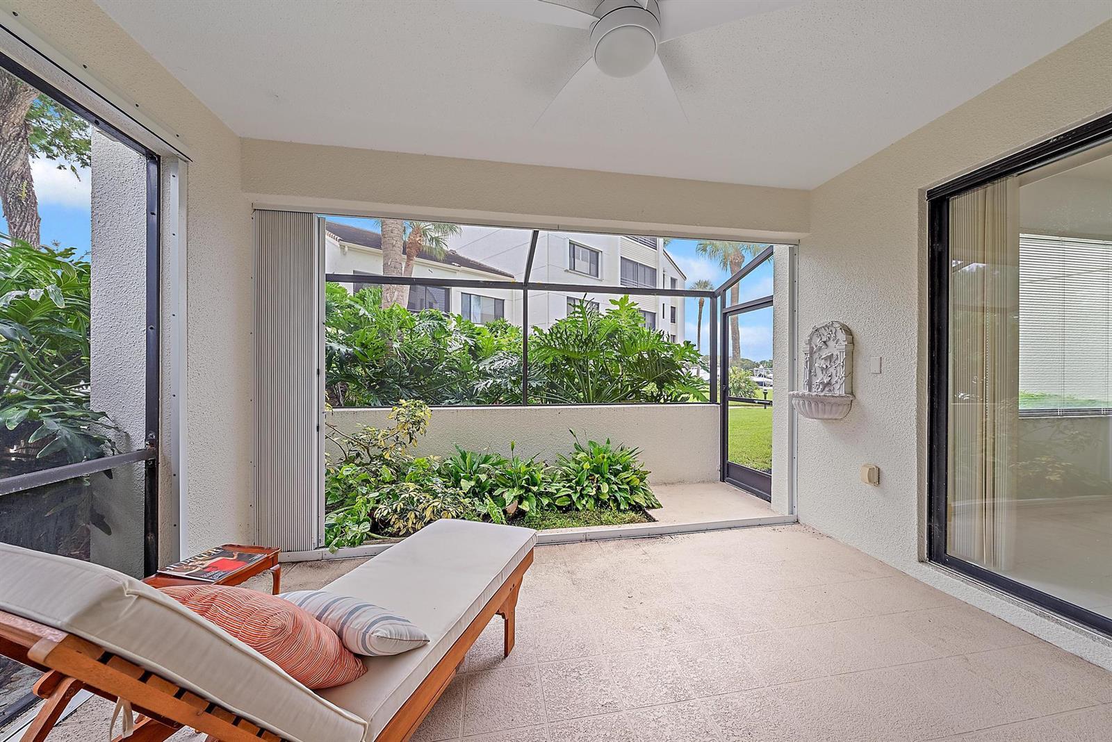 A screened-in patio features a lounge chair, a wall-mounted fountain, and views of greenery — 811 Oak Harbour Drive, Juno Beach FL 33408, JUNO BEACH, FL