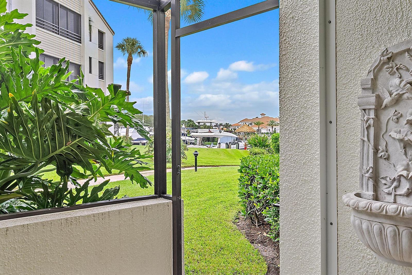 A view of a grassy lawn and a marina from a screened-in patio — 811 Oak Harbour Drive, Juno Beach FL 33408, JUNO BEACH, FL