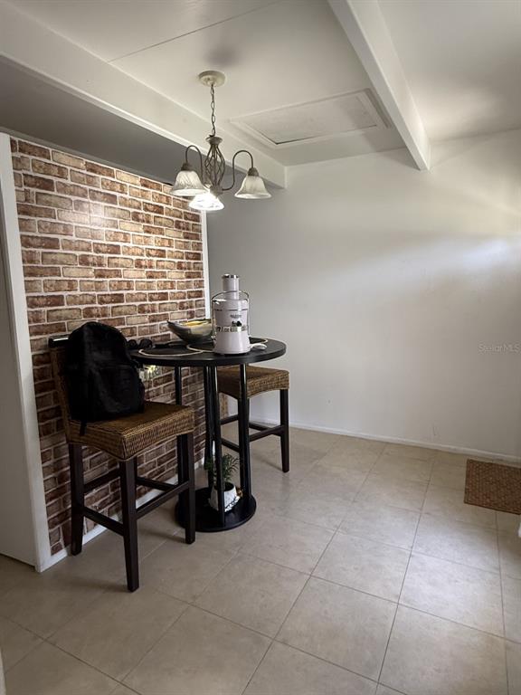 A dining area features a brick accent wall, a round table with two stools, and a chandelier — 4719 CLUB CIRCLE, LAKE WALES, FL