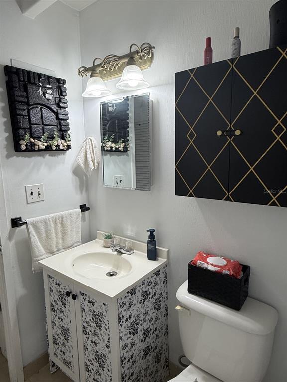 A bathroom features a floral-patterned vanity, a black and gold cabinet, and a wall mirror — 4719 CLUB CIRCLE, LAKE WALES, FL