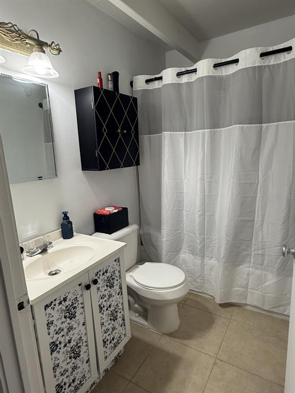 A bathroom features a floral-patterned vanity, a black wall cabinet, and a gray-and-white shower curtain — 4719 CLUB CIRCLE, LAKE WALES, FL