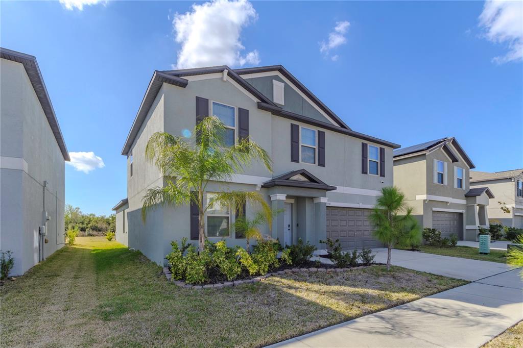 A two-story suburban house with a gray stucco exterior and a two-car garage — 15541 COLT CREEK PLACE, SUN CITY CENTER, FL