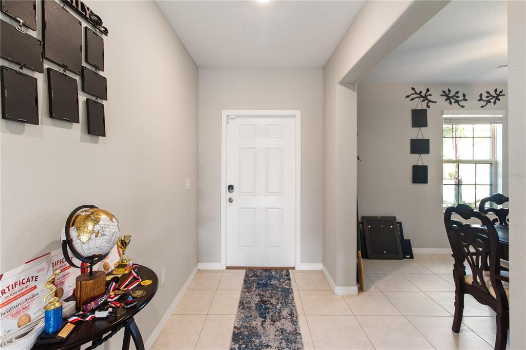 An entryway with a white door, tile flooring, and a small table with a globe — 15541 COLT CREEK PLACE, SUN CITY CENTER, FL