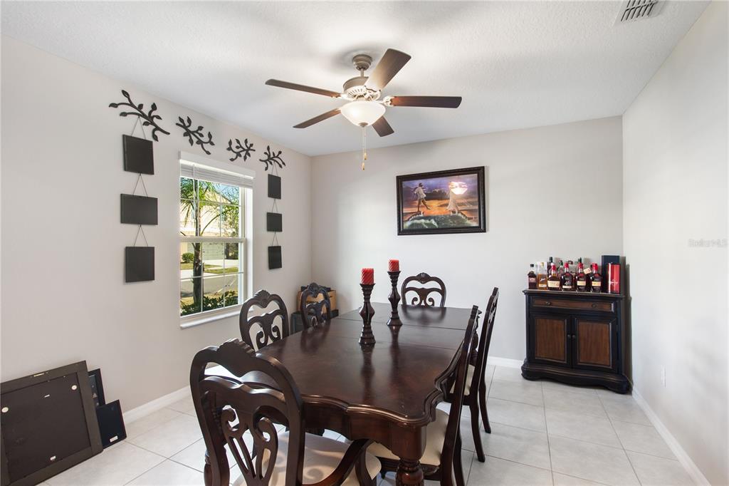A dining room features a dark wood table, matching chairs, and a liquor cabinet — 15541 COLT CREEK PLACE, SUN CITY CENTER, FL