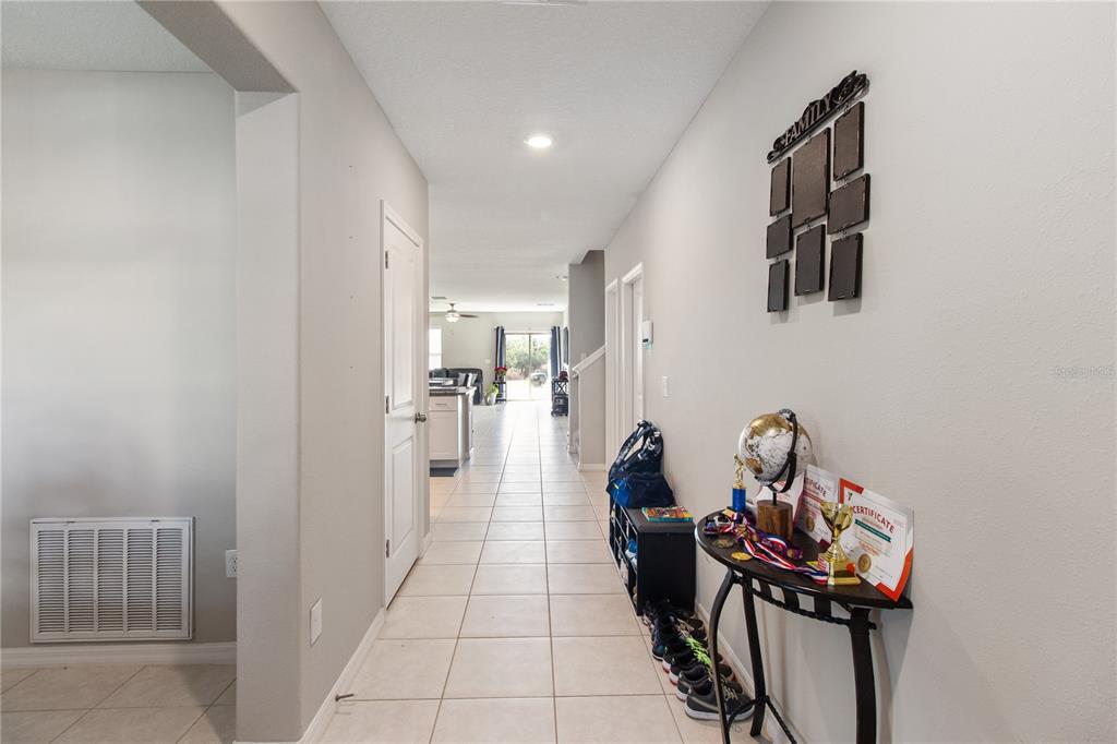 A hallway with tile flooring leads toward an open living area with a kitchen — 15541 COLT CREEK PLACE, SUN CITY CENTER, FL