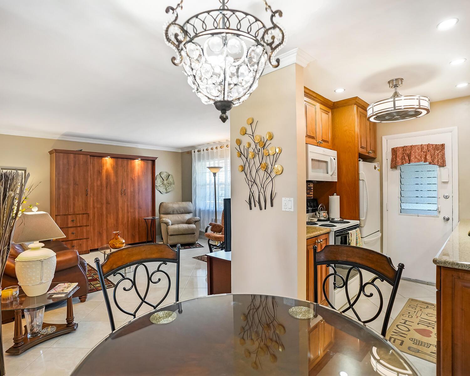 A dining area with a glass table overlooks a living room and a small kitchen — 16801 NE 13th Avenue # 308, Miami FL 33162, MIAMI, FL