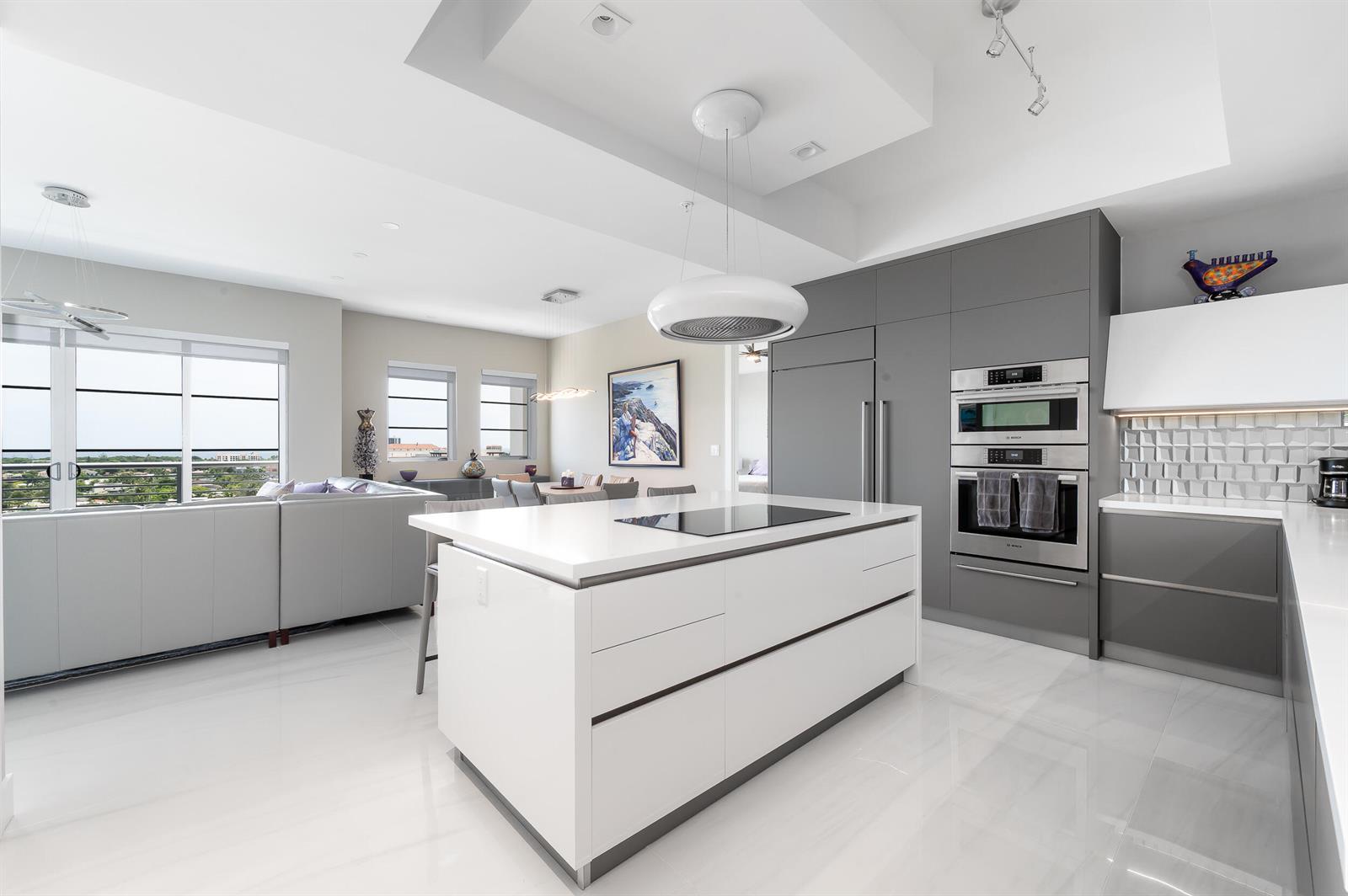 A modern kitchen features a white island, gray cabinetry, stainless steel appliances, and tile flooring — 155 E Boca Raton Road # 1107, Boca Raton FL 33432, BOCA RATON, FL