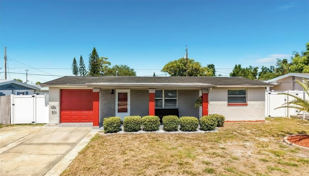 A single-story house with a red garage door, red pillars, and a gray brick facade — 2019 HESS DRIVE, HOLIDAY, FL