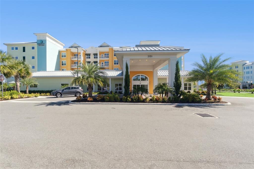 The exterior of a multi-story hotel with a covered entrance and palm trees — 3151 SUNSET WALK DRIVE UNIT 1202, KISSIMMEE, FL