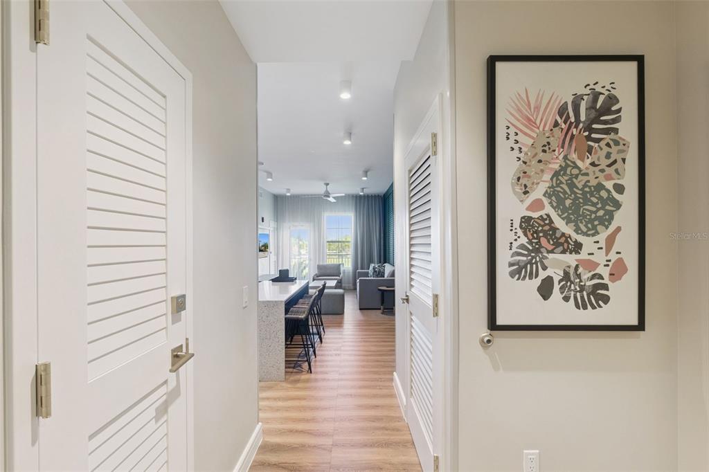A hallway with louvered doors leads to an open-concept kitchen and living area — 3151 SUNSET WALK DRIVE UNIT 1202, KISSIMMEE, FL