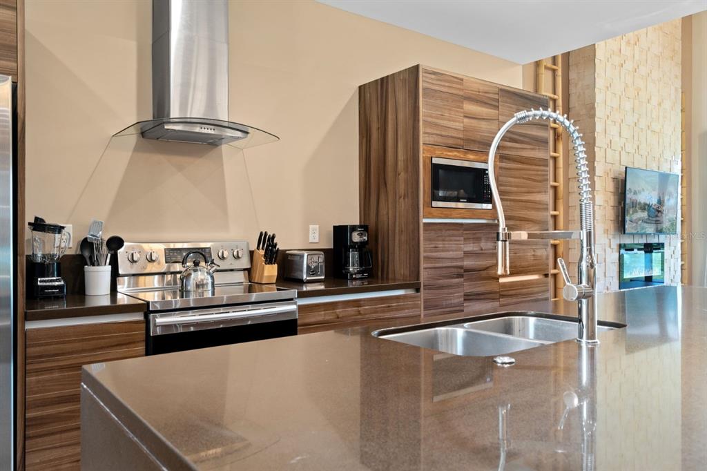 A modern kitchen features wood-grain cabinets, stainless steel appliances, and a large brown countertop — 3092 ROCKEFELLER WAY, KISSIMMEE, FL