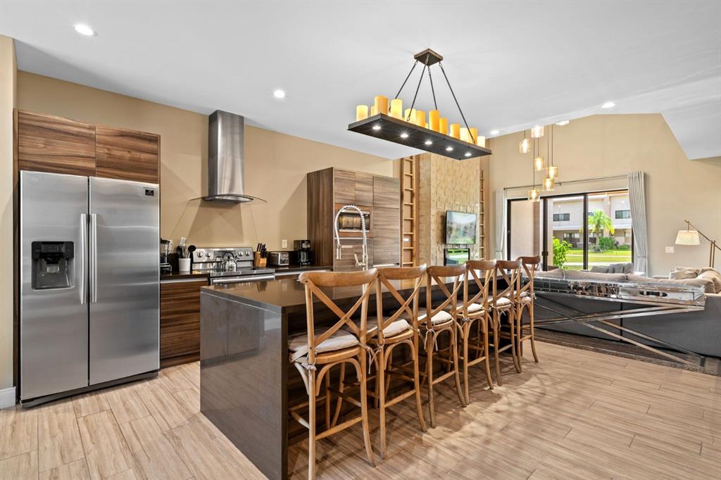 A modern kitchen features wood cabinets, stainless steel appliances, and a large island with seating — 3092 ROCKEFELLER WAY, KISSIMMEE, FL