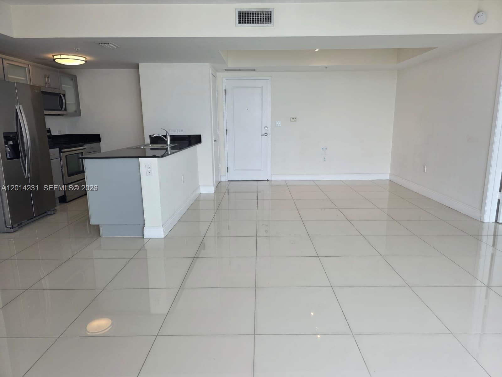 An open-concept kitchen with stainless steel appliances and a breakfast bar overlooks a tiled room — 1861 NW S River Dr # 2603, Miami FL 33125, MIAMI, FL
