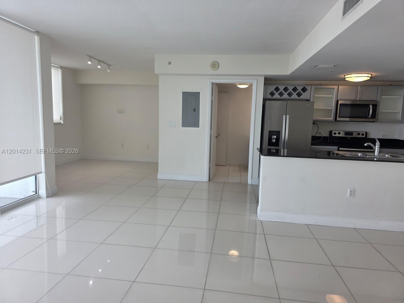 An open-concept living area features white tile floors, a kitchen with stainless appliances, and a doorway — 1861 NW S River Dr # 2603, Miami FL 33125, MIAMI, FL