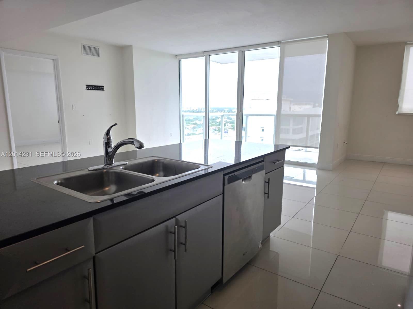 A kitchen island with a double sink and stainless steel dishwasher sits in a bright room — 1861 NW S River Dr # 2603, Miami FL 33125, MIAMI, FL
