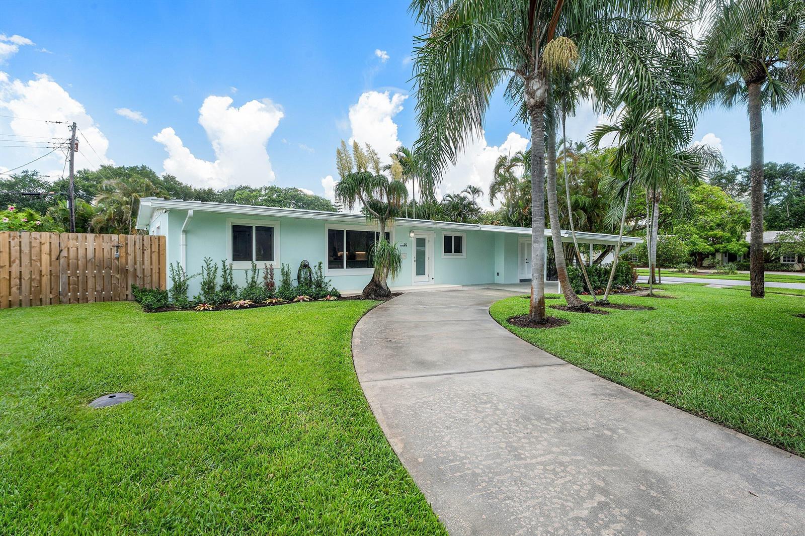 A light blue single-story house features a curved concrete driveway and several tall palm trees — 945 Westwind Drive, North Palm Beach FL 33408, NORTH PALM BEACH, FL