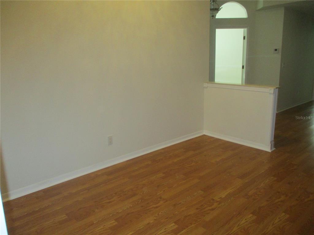 An empty room features light-colored walls, wood-look flooring, and a half-wall partition — 209 N BROCKFIELD DRIVE, SUN CITY CENTER, FL