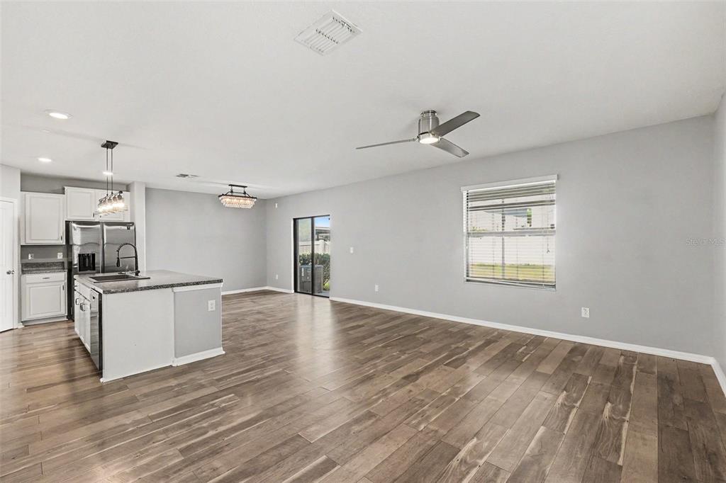 An open-concept kitchen and living area features light gray walls and wood-look flooring — 14803 EMERALD LANDING PLACE, WIMAUMA, FL
