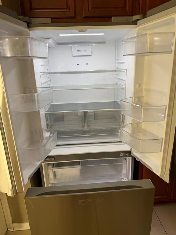 An open stainless steel refrigerator with multiple glass shelves and clear storage bins — 1403 KISSIMMEE COURT, KISSIMMEE, FL