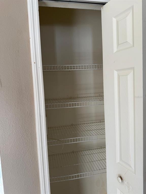 A narrow closet features white wire shelving and a paneled door — 1403 KISSIMMEE COURT, KISSIMMEE, FL