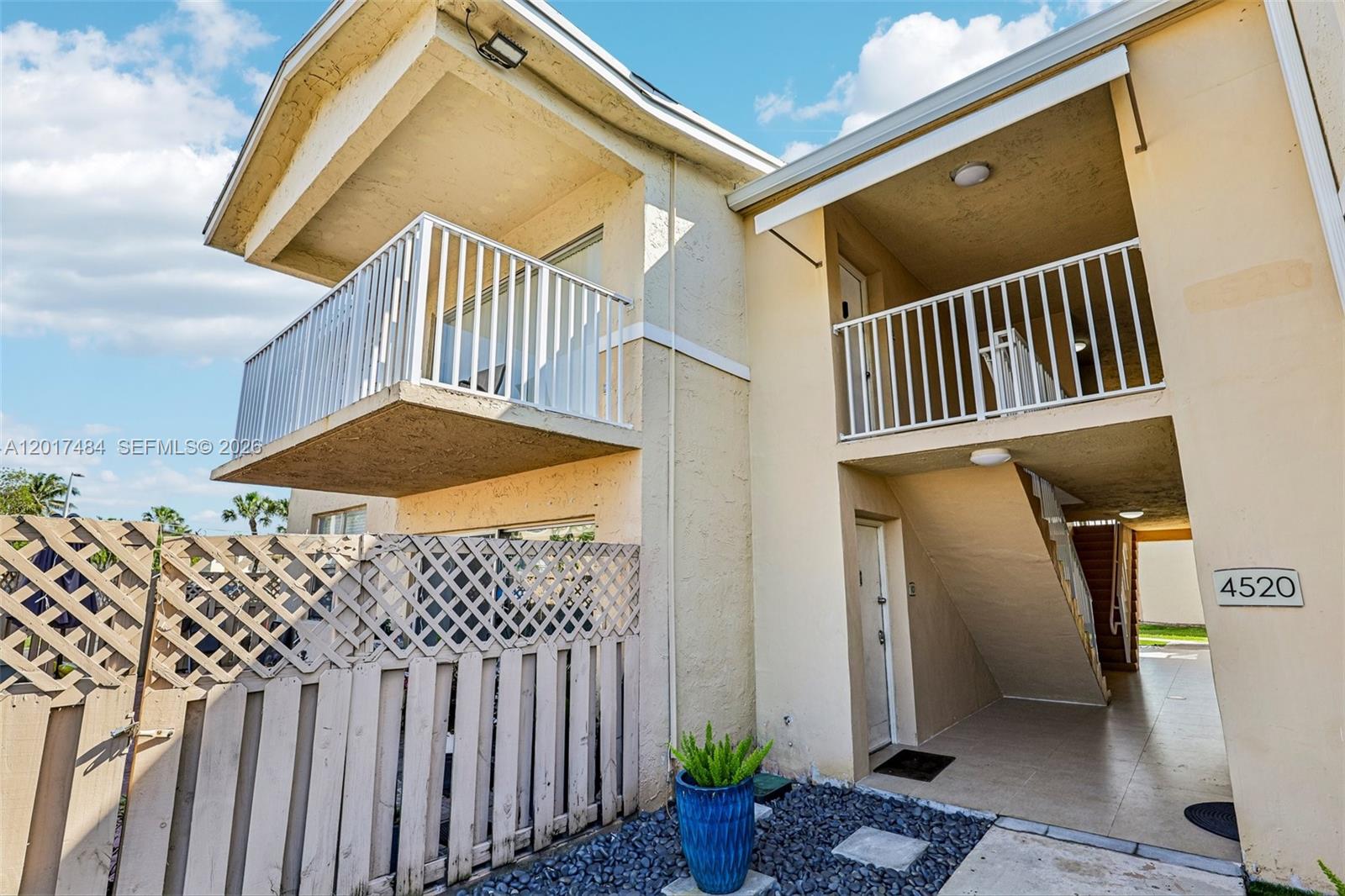A two-story apartment building exterior features a balcony, a staircase, and a lattice fence — 4520 NW 79th Ave # 2D, Doral FL 33166, DORAL, FL