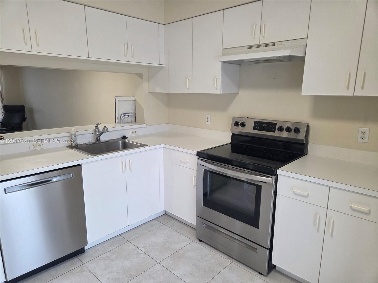 A kitchen features white cabinets, stainless steel appliances, a sink, and light-colored tile flooring — 47 Simonton Cir, Weston FL 33326, WESTON, FL
