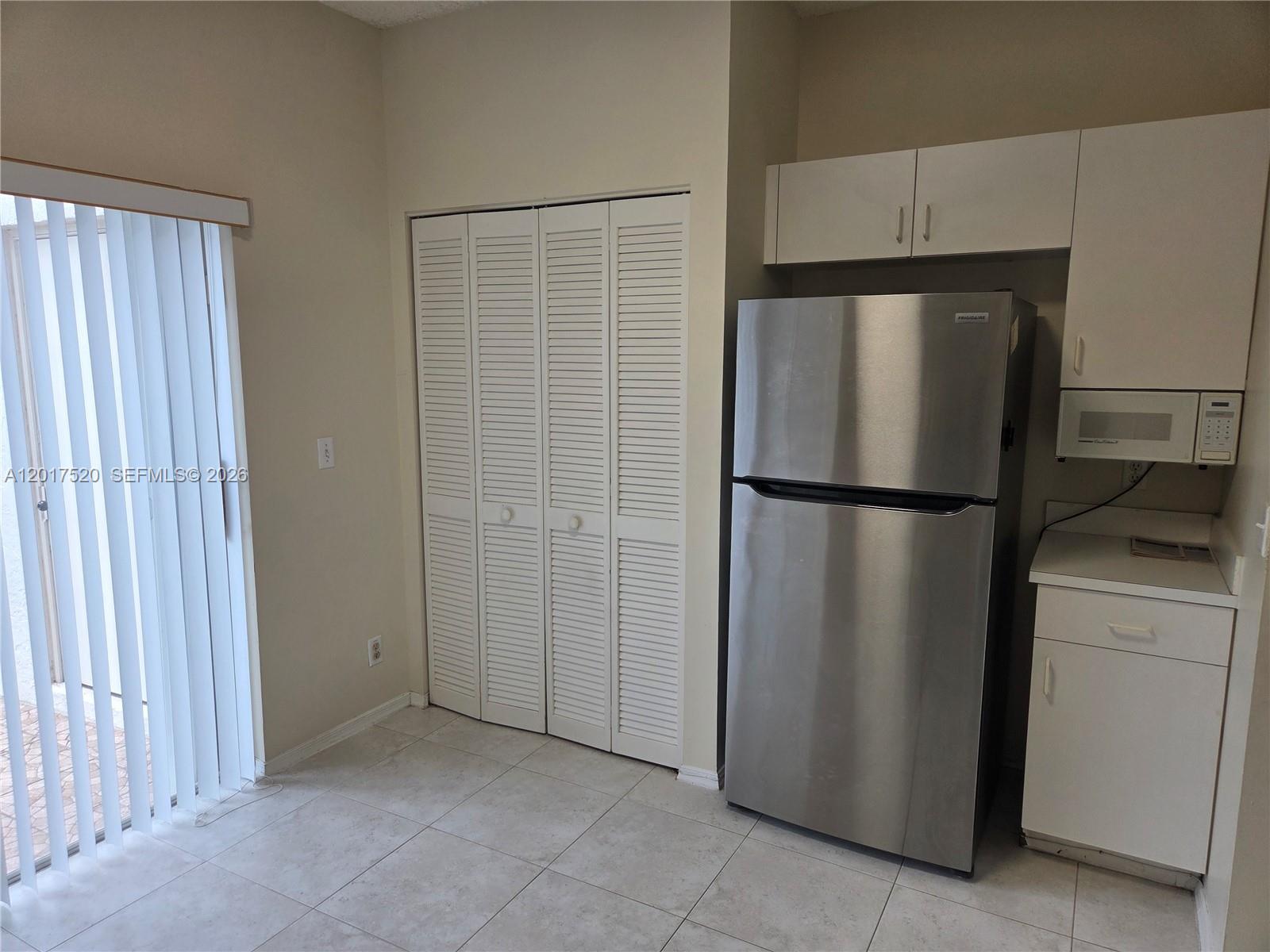 A kitchen area features a stainless steel refrigerator, white cabinetry, and a louvered closet door — 47 Simonton Cir, Weston FL 33326, WESTON, FL