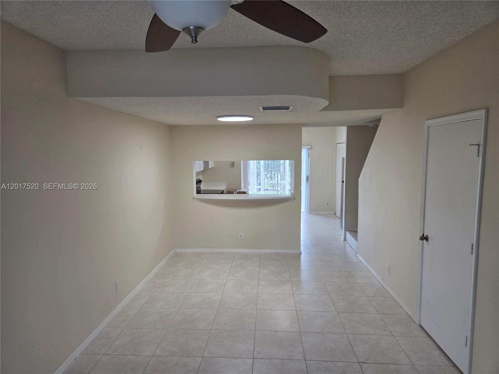 This room features light-colored tile flooring, a pass-through window to the kitchen, and a ceiling fan — 47 Simonton Cir, Weston FL 33326, WESTON, FL
