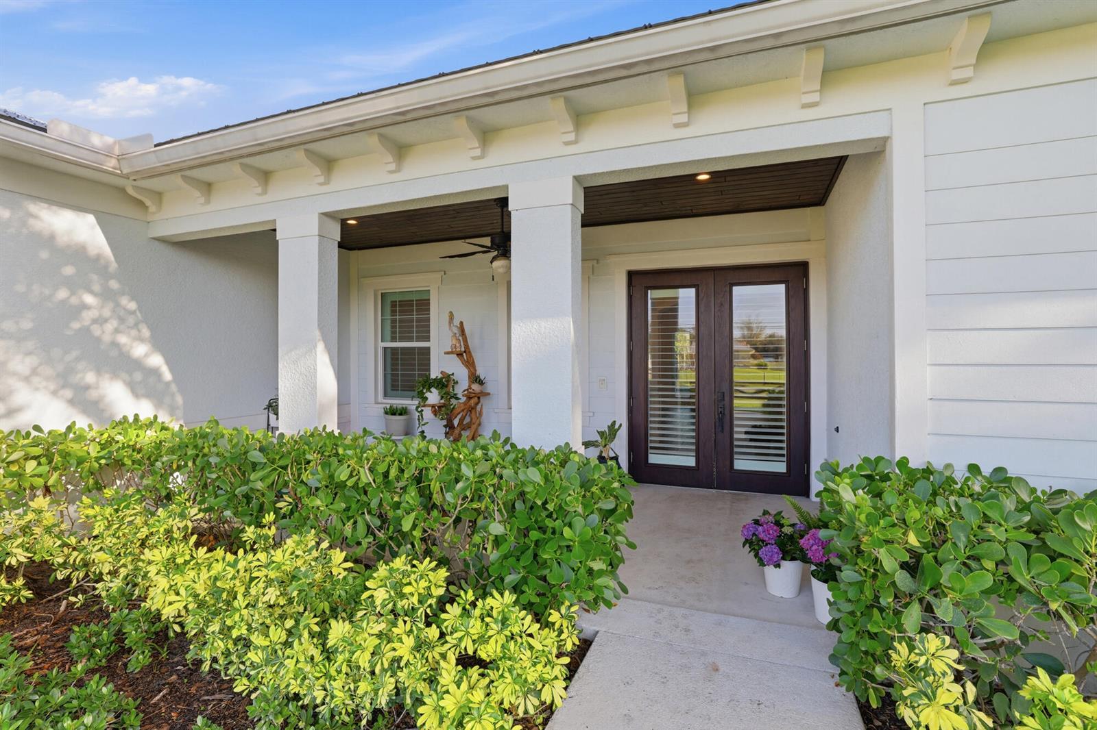 The exterior of a house features a covered porch with white columns and double doors — 9301 154th Road N, Jupiter FL 33478, JUPITER, FL