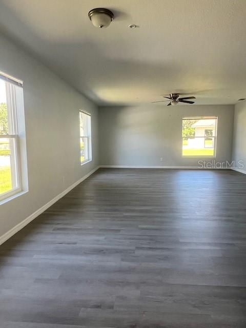 An empty room features light gray walls, wood-look flooring, a ceiling fan, and two windows — 4076 OAK LOOP UNIT 4076, MULBERRY, FL