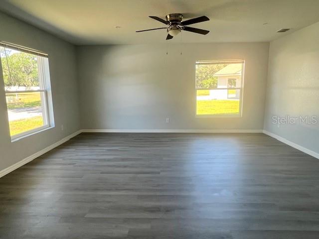 An empty room features gray wood-look flooring, a ceiling fan, and two windows — 4076 OAK LOOP UNIT 4076, MULBERRY, FL