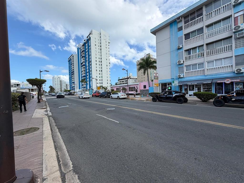 A street view shows multi-story apartment buildings, parked vehicles, and a sidewalk under a blue sky — 37 ISLA VERDE AVENUE UNIT 4C, CAROLINA, PR