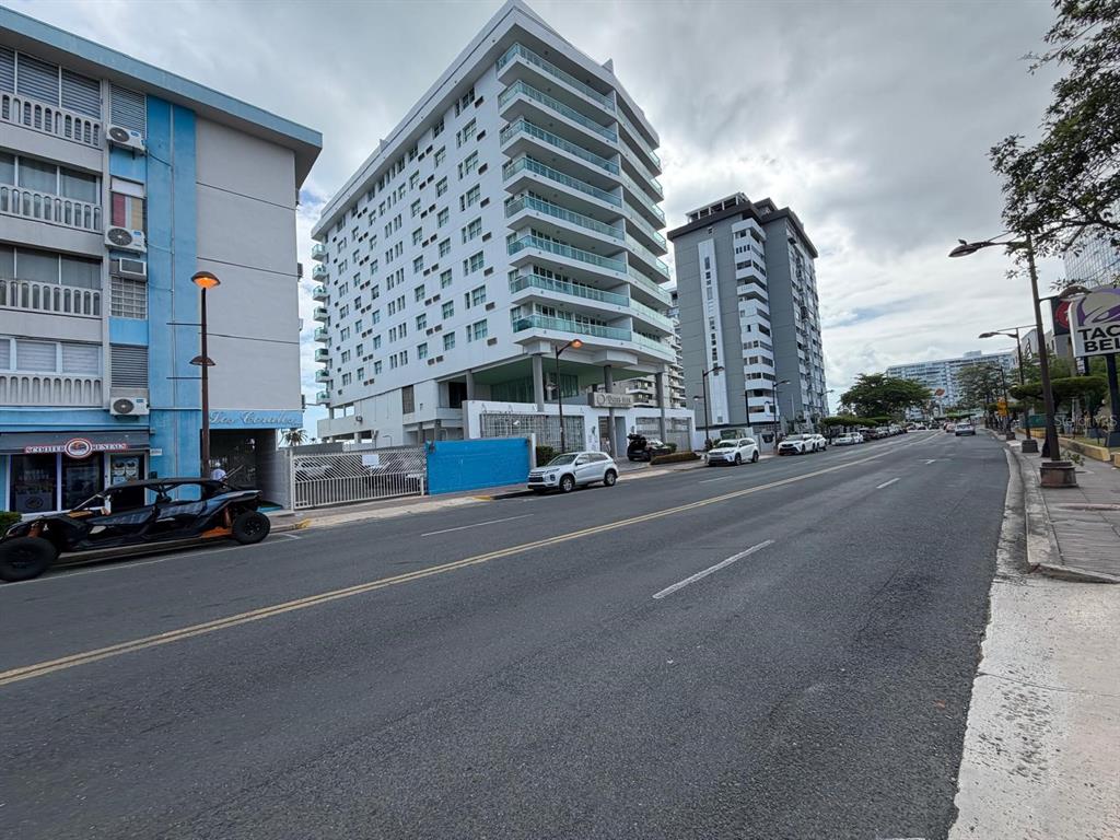 A street-level view shows a multi-story white apartment building next to a blue building — 37 ISLA VERDE AVENUE UNIT 4C, CAROLINA, PR