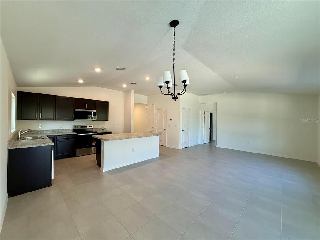 A kitchen with dark cabinets and a breakfast bar opens into a large living area — 20248 LAVENDER BLOOM, MOUNT DORA, FL