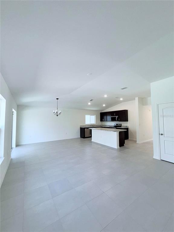 An open-concept kitchen with dark cabinets and a central island overlooks a large tiled room — 20248 LAVENDER BLOOM, MOUNT DORA, FL