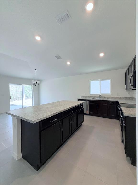 A kitchen features dark cabinets, light countertops, an island, and recessed lighting — 20248 LAVENDER BLOOM, MOUNT DORA, FL
