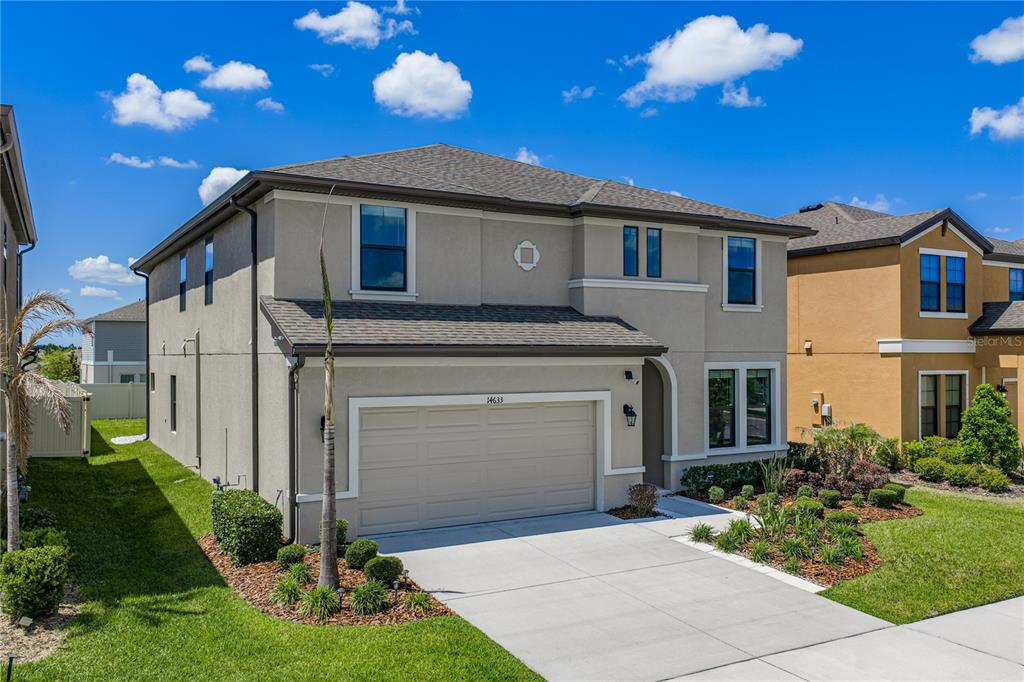 A two-story suburban house with a beige stucco exterior and a two-car garage — 14633 RED CASTLE AVENUE, LITHIA, FL