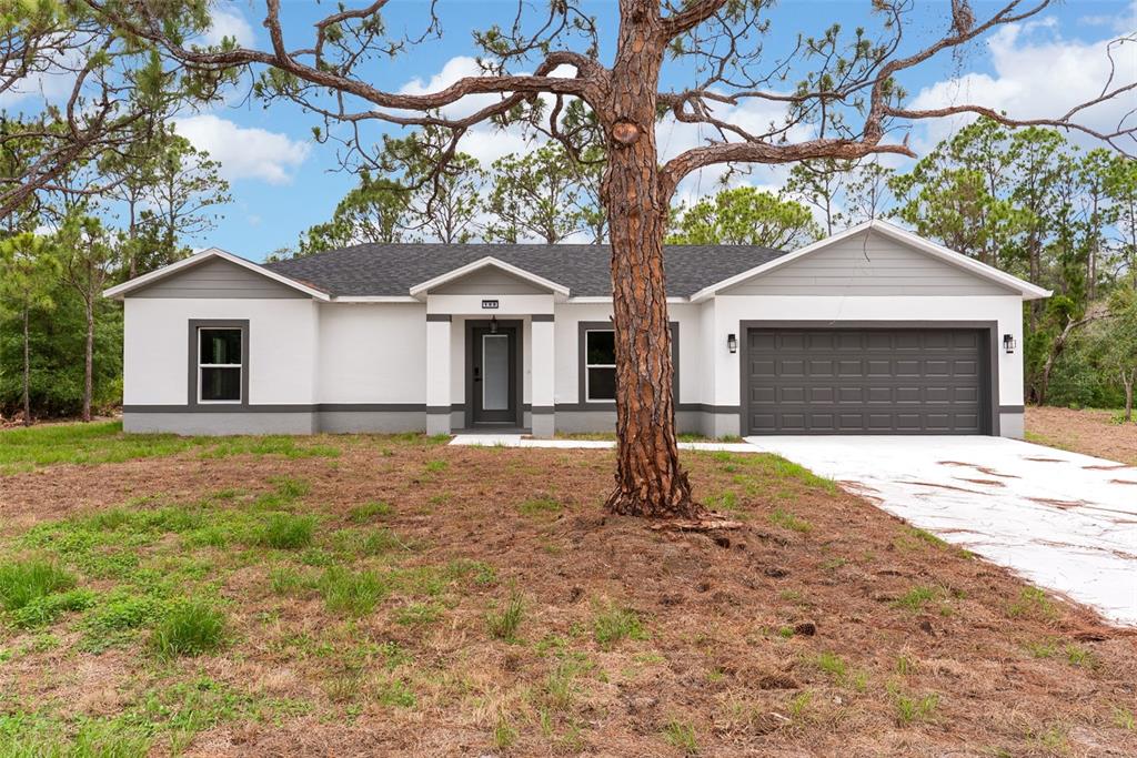 A single-story house with a white stucco exterior, gray trim, and a two-car garage — 108 OXBOW DRIVE, SEBRING, FL