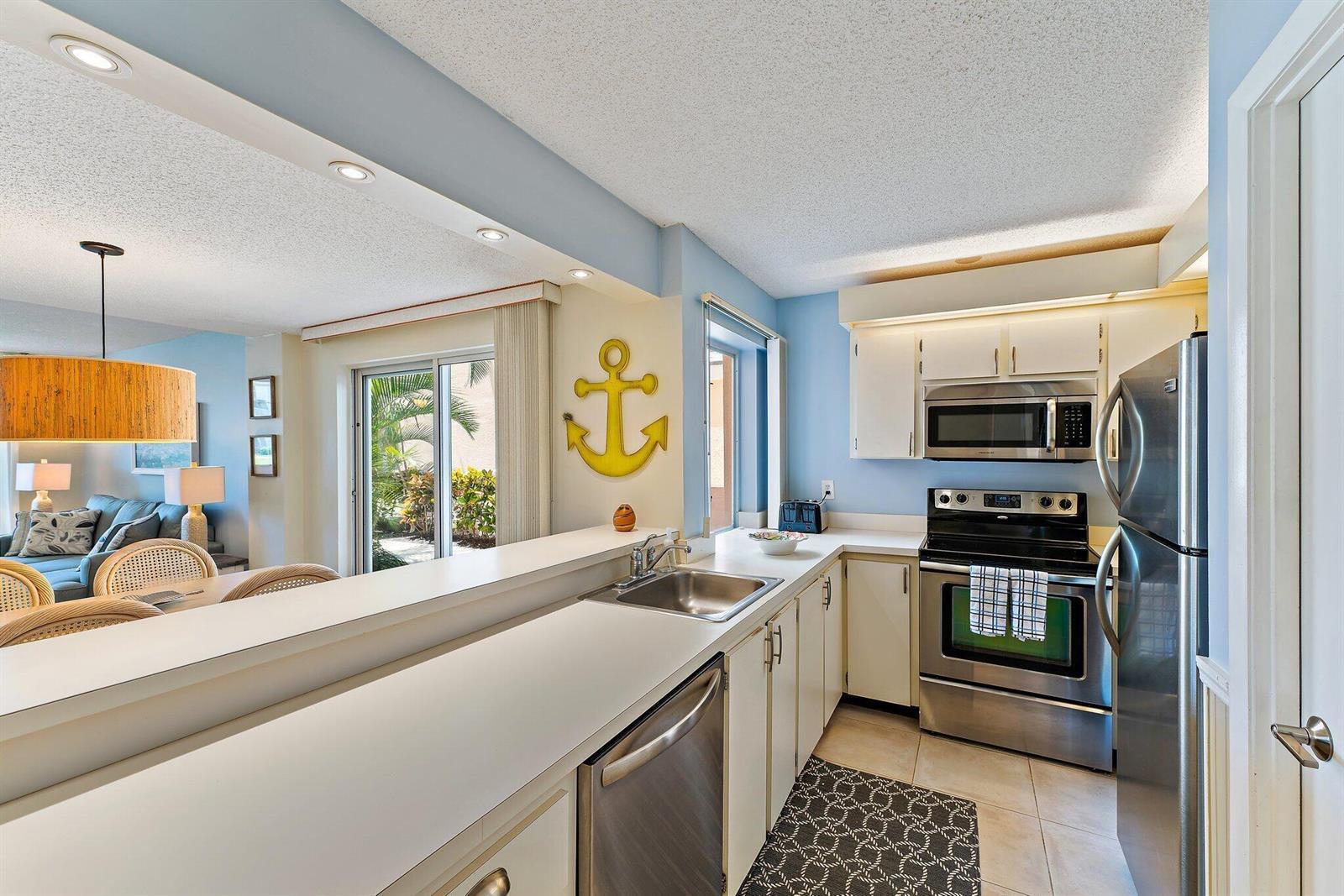 A kitchen with white cabinets, stainless steel appliances, and a yellow anchor wall decoration — 353 S Us Highway 1 # A105, Jupiter FL 33477, JUPITER, FL