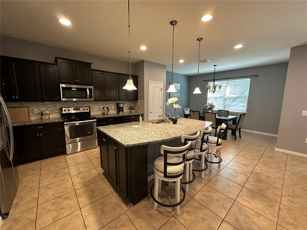 A living room features a dark stone accent wall, a sectional sofa, and tile flooring — 1869 NICE COURT, KISSIMMEE, FL