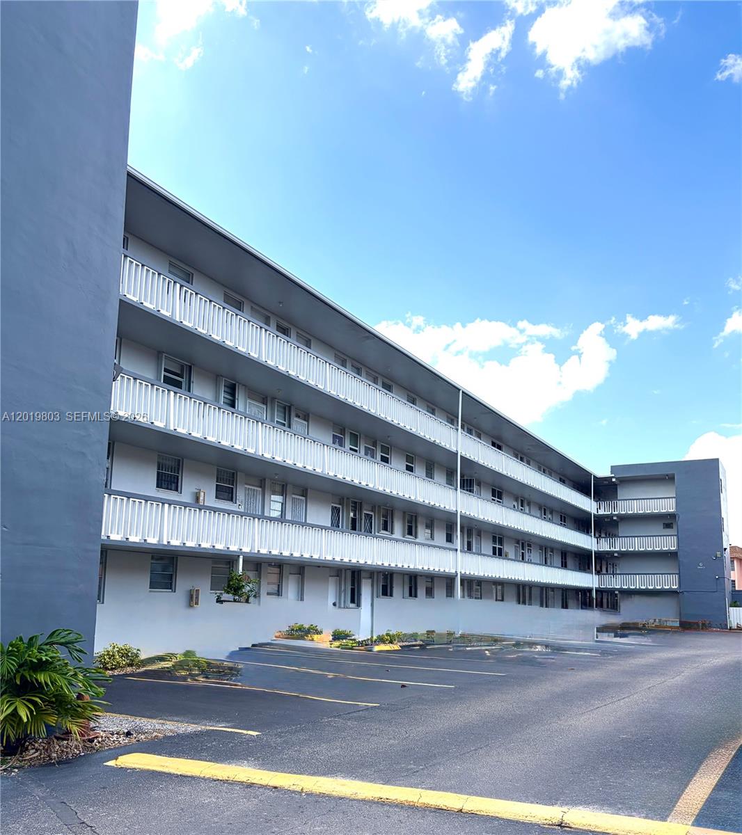 A multi-story apartment building features exterior walkways with white railings and an adjacent parking lot — 18601 NE 14th ave # 301, Miami FL 33179, MIAMI, FL