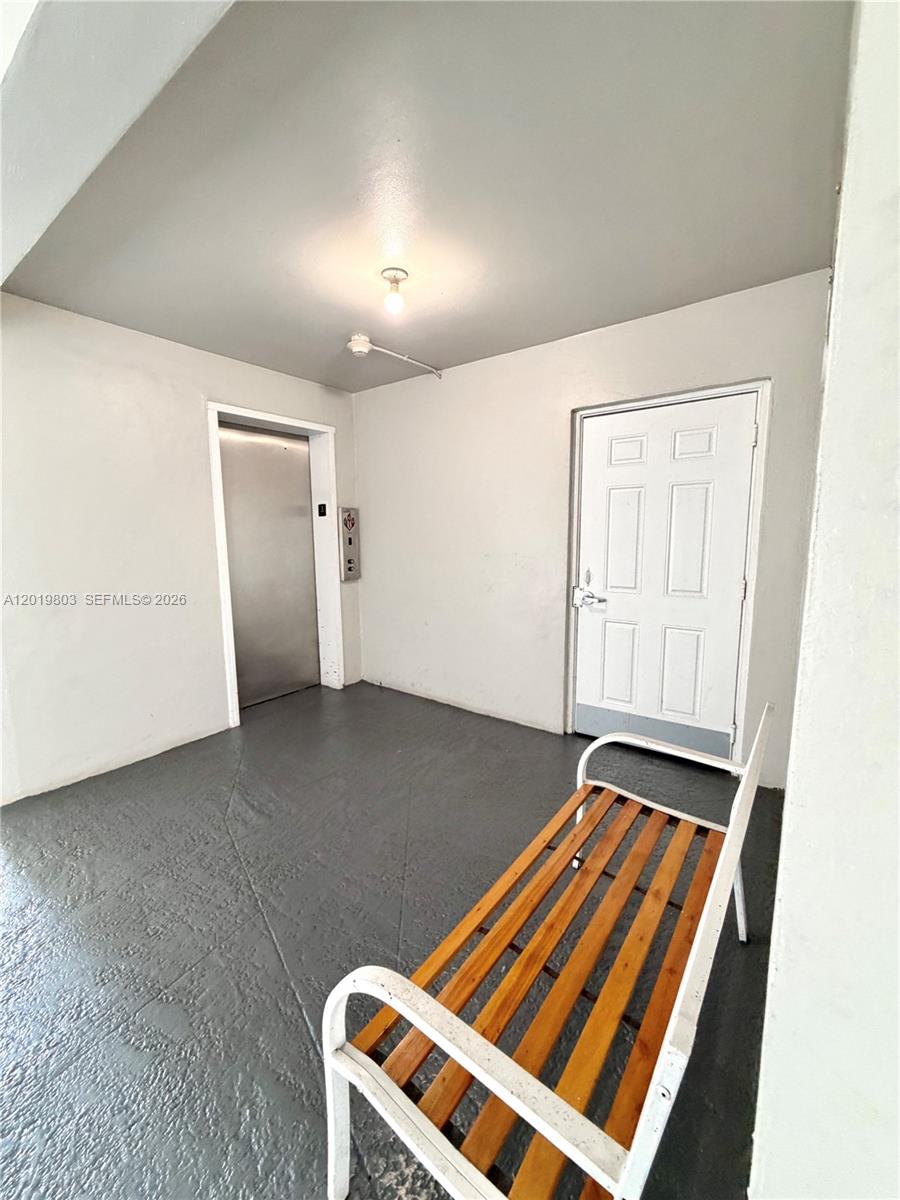 A small indoor landing features a metal elevator, a white door, and a wooden bench — 18601 NE 14th ave # 301, Miami FL 33179, MIAMI, FL