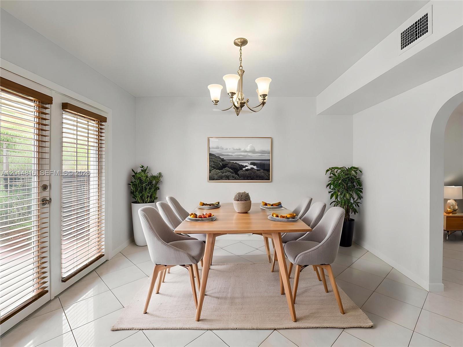 A dining room features a wooden table, six grey chairs, a chandelier, and tile flooring — 951 E 18th St, Hialeah FL 33013, HIALEAH, FL