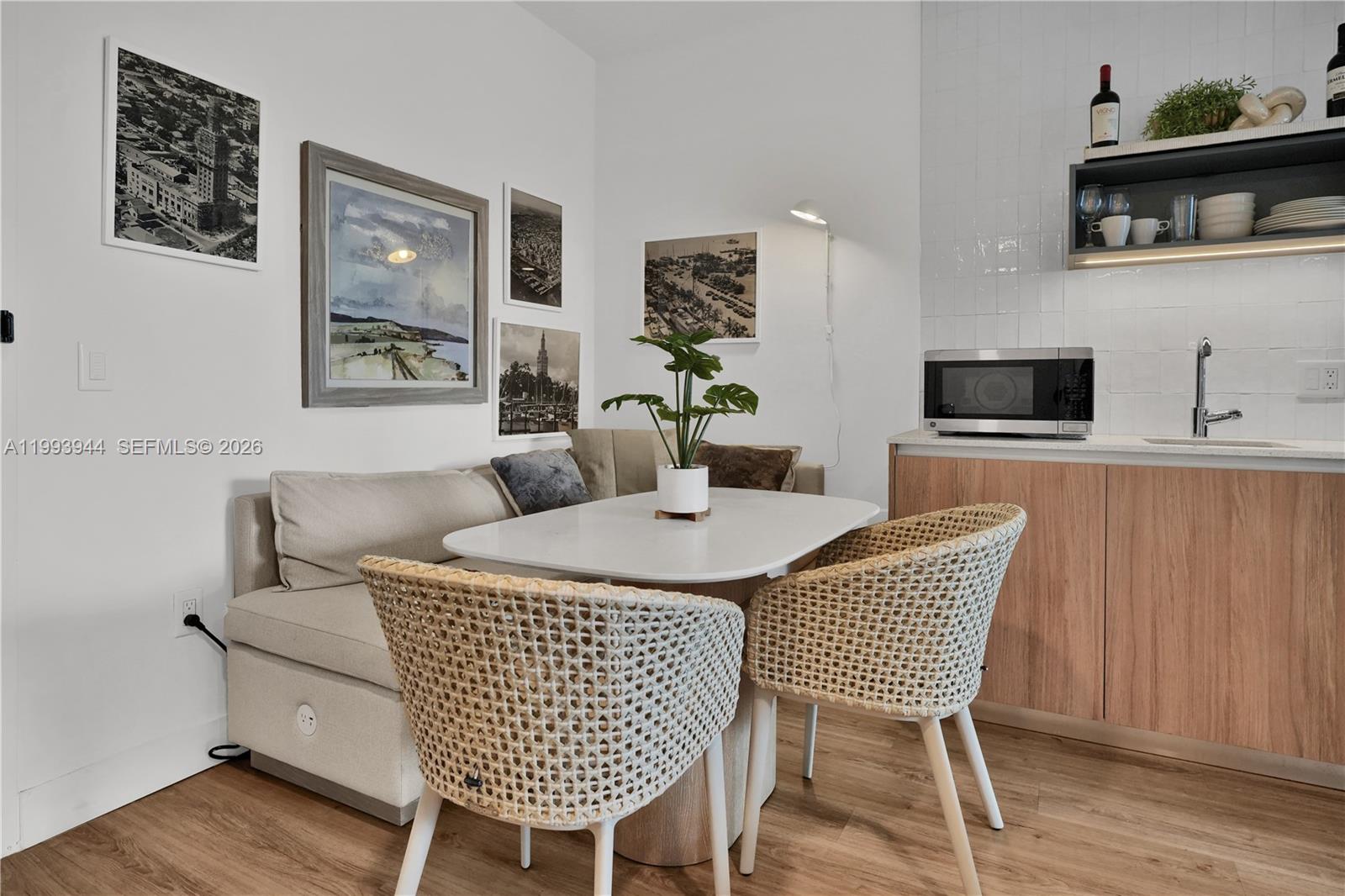 A dining area features a corner banquette, two woven chairs, and a small kitchenette — 159 NE 6th St # 1809, Miami FL 33132, MIAMI, FL