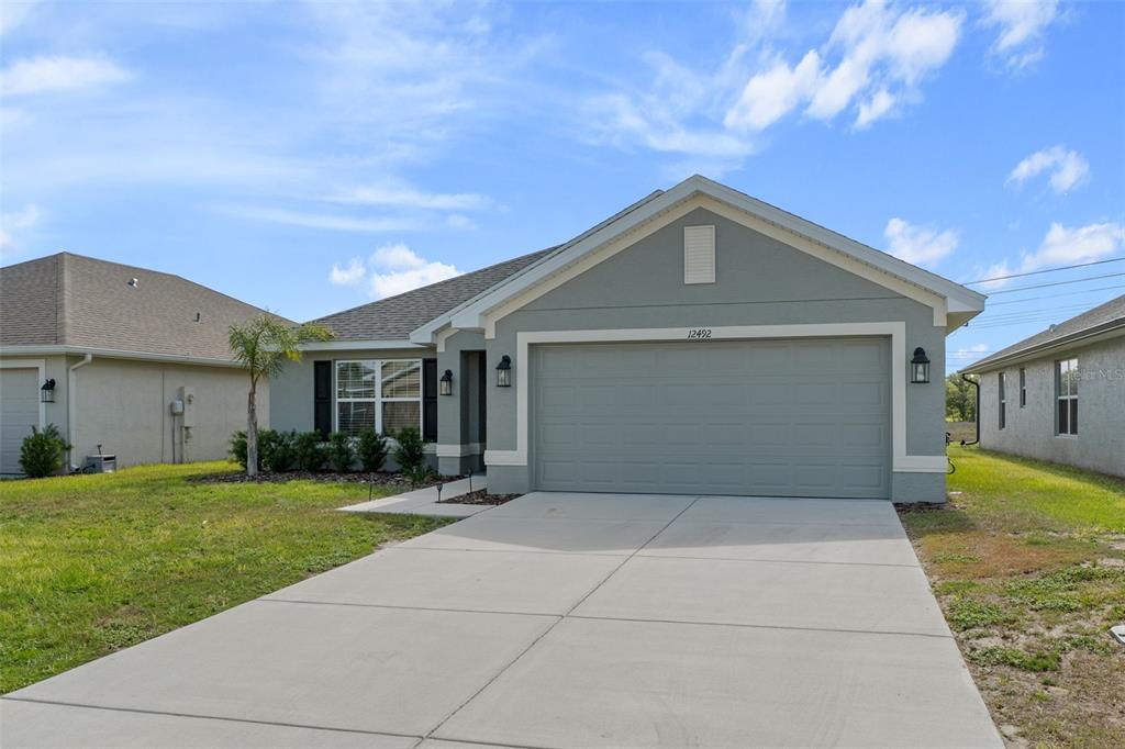 A single-story house with a gray exterior, a two-car garage, and a concrete driveway — 12492 PINE BLUFF STREET, SPRING HILL, FL