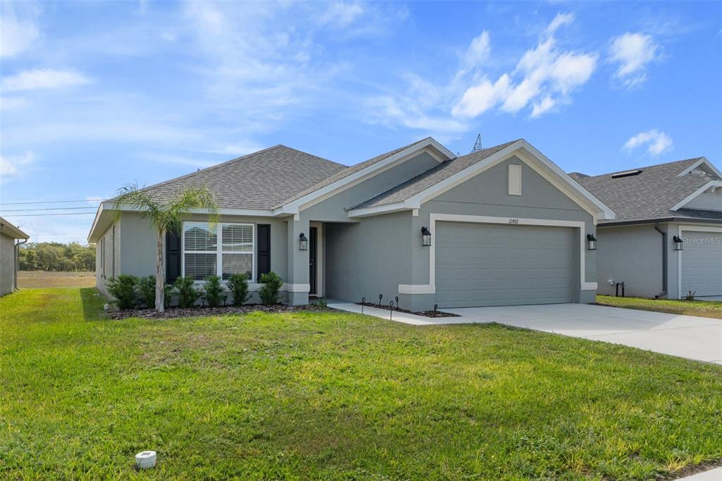 A single-story house with a gray exterior, a two-car garage, and a small front lawn — 12492 PINE BLUFF STREET, SPRING HILL, FL