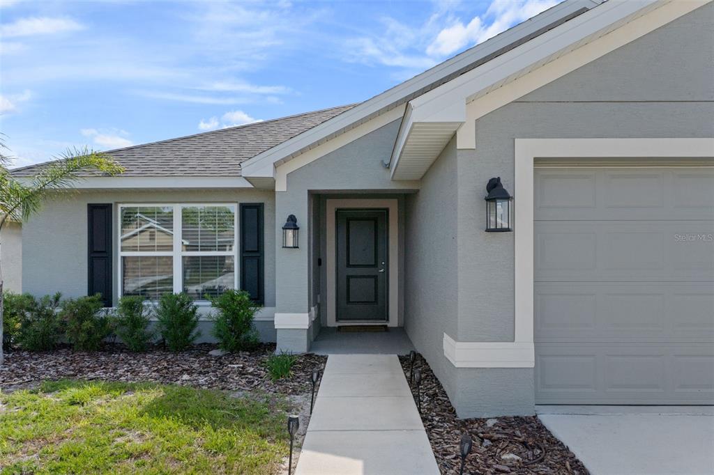 The exterior of a gray house features a front door, a garage, and a walkway — 12492 PINE BLUFF STREET, SPRING HILL, FL
